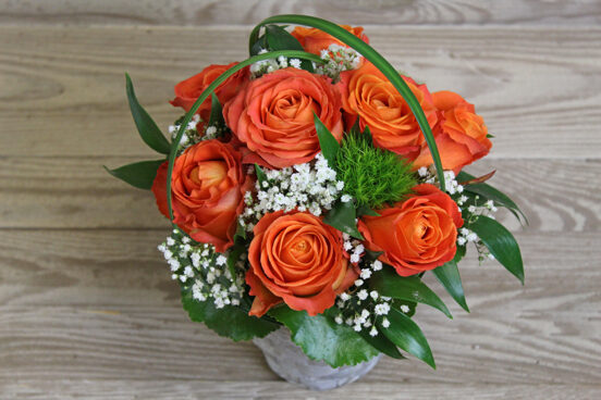 Small orange rose arrangement in a basket